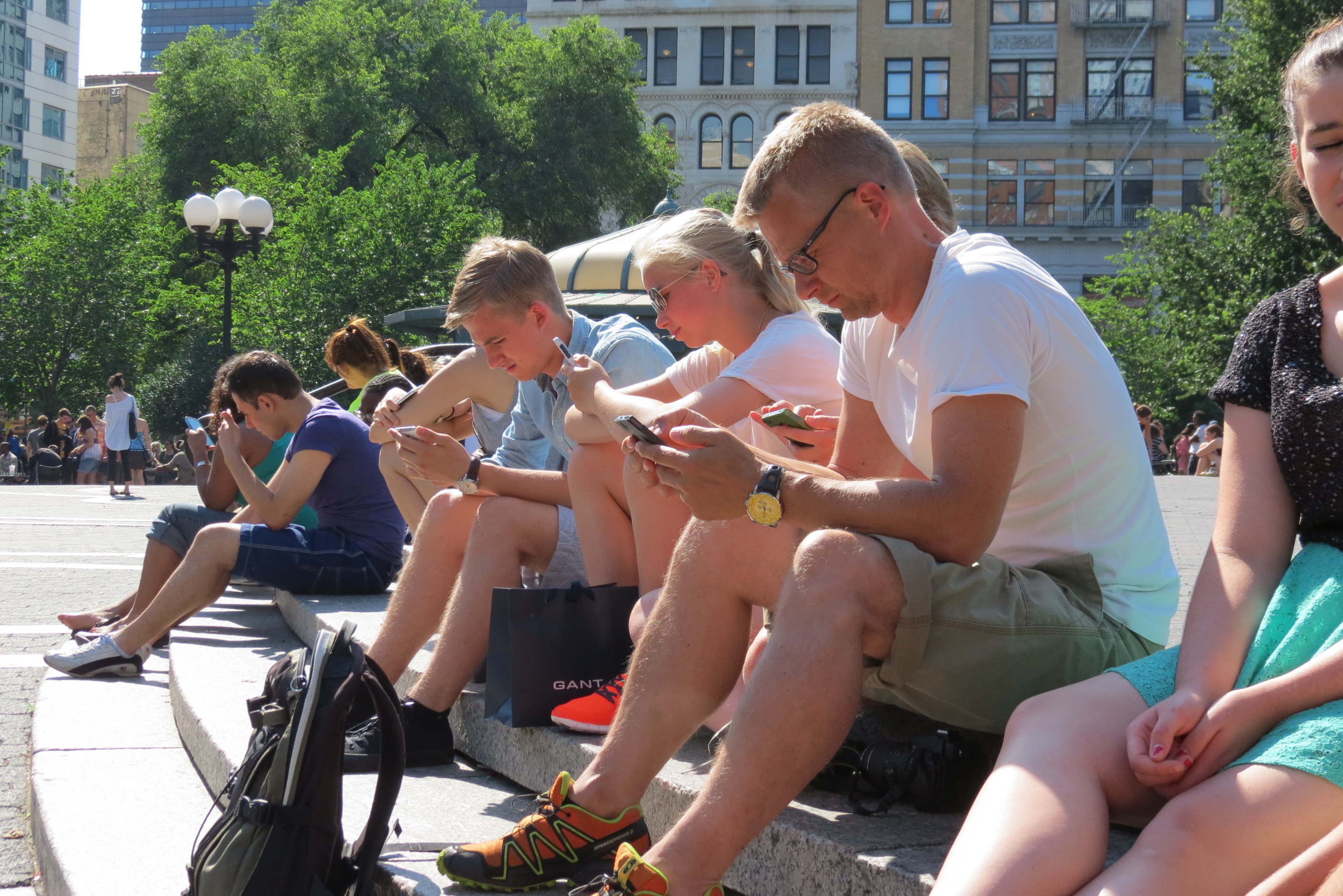 A tourist family in New York City ignore each other & stare at their phones