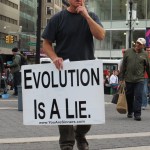 street preacher holding EVOLUTION IS A LIE sign