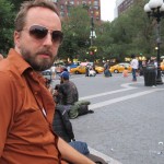 bearded man in brown shirt & shades
