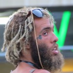 bearded man with flamboyant shades and snake tattoo near eye