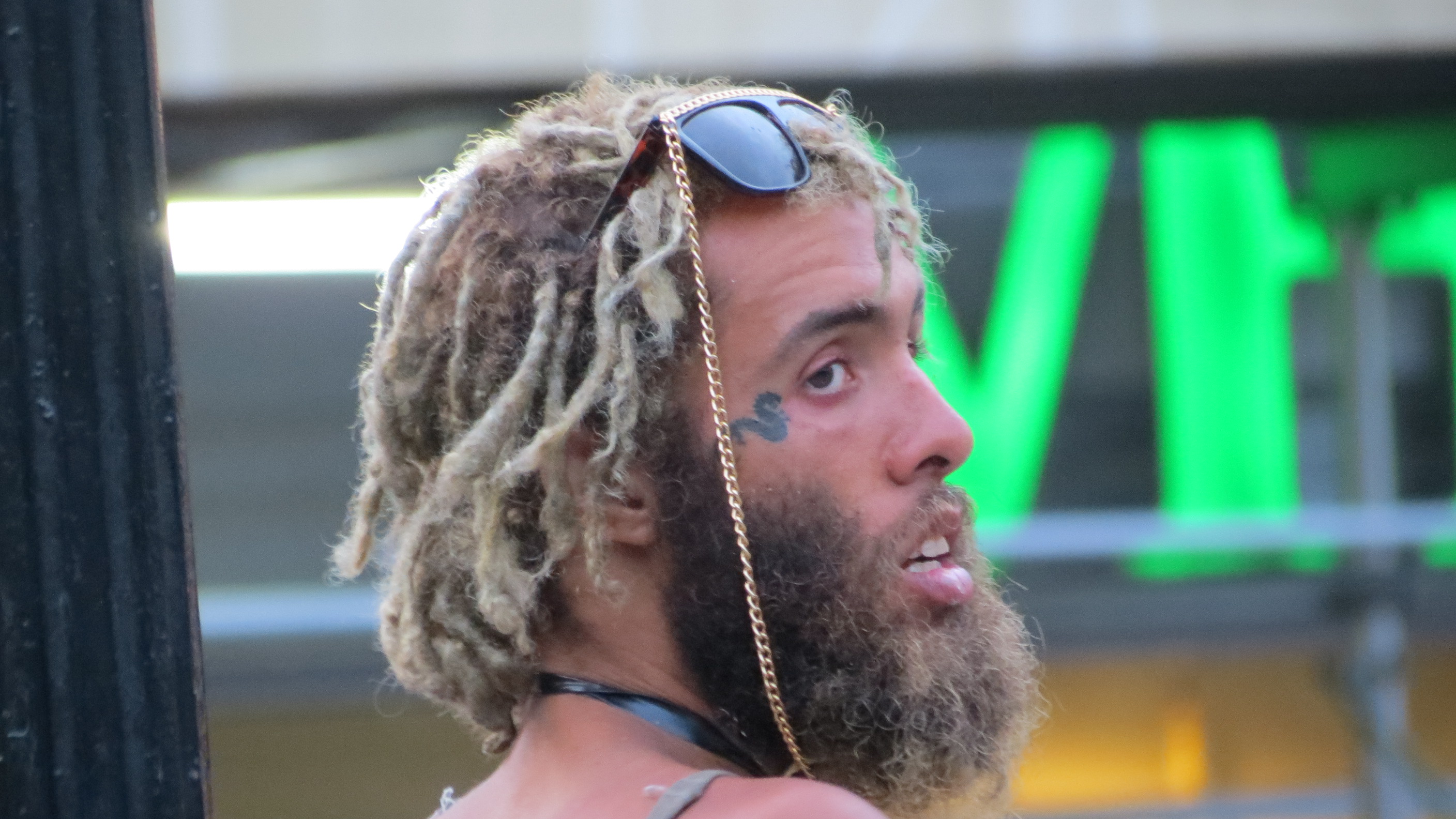 bearded man with flamboyant shades and snake tattoo near eye