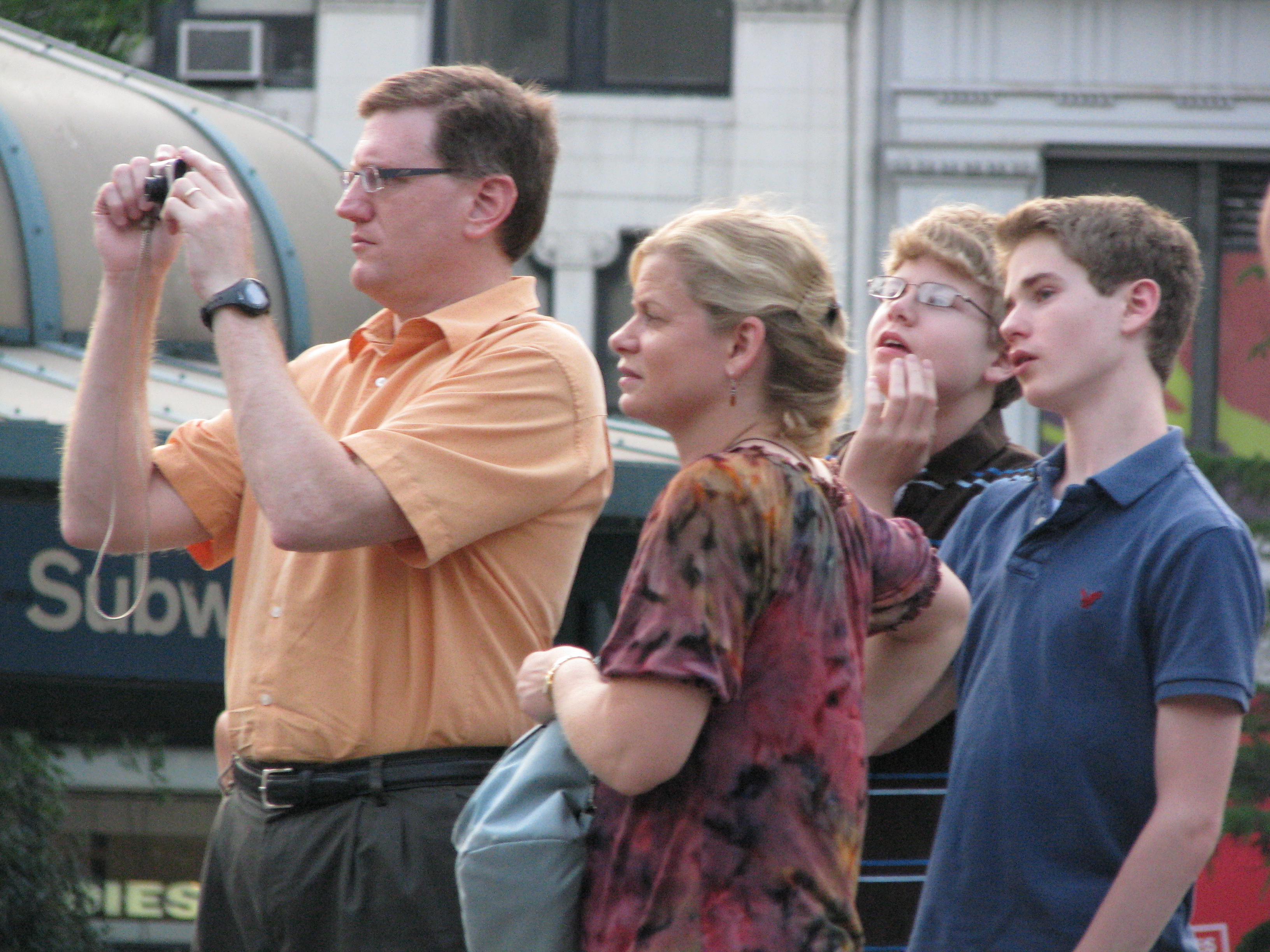 Father in a family of tourists taking a picture of NYC
