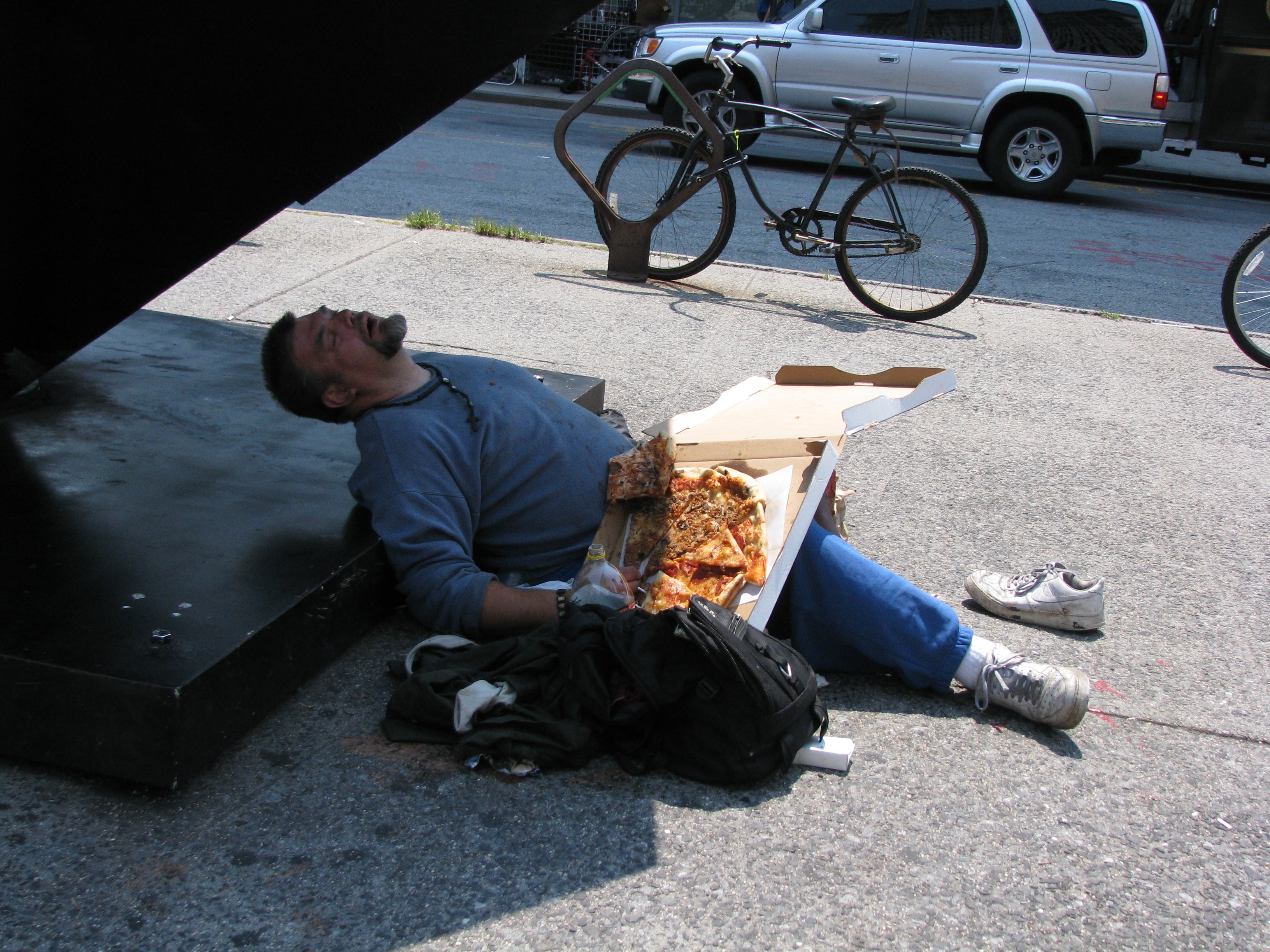 Man asleep under The Cube with pizza