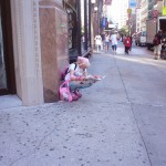 Pink girl reading paper up the street from Strand Books