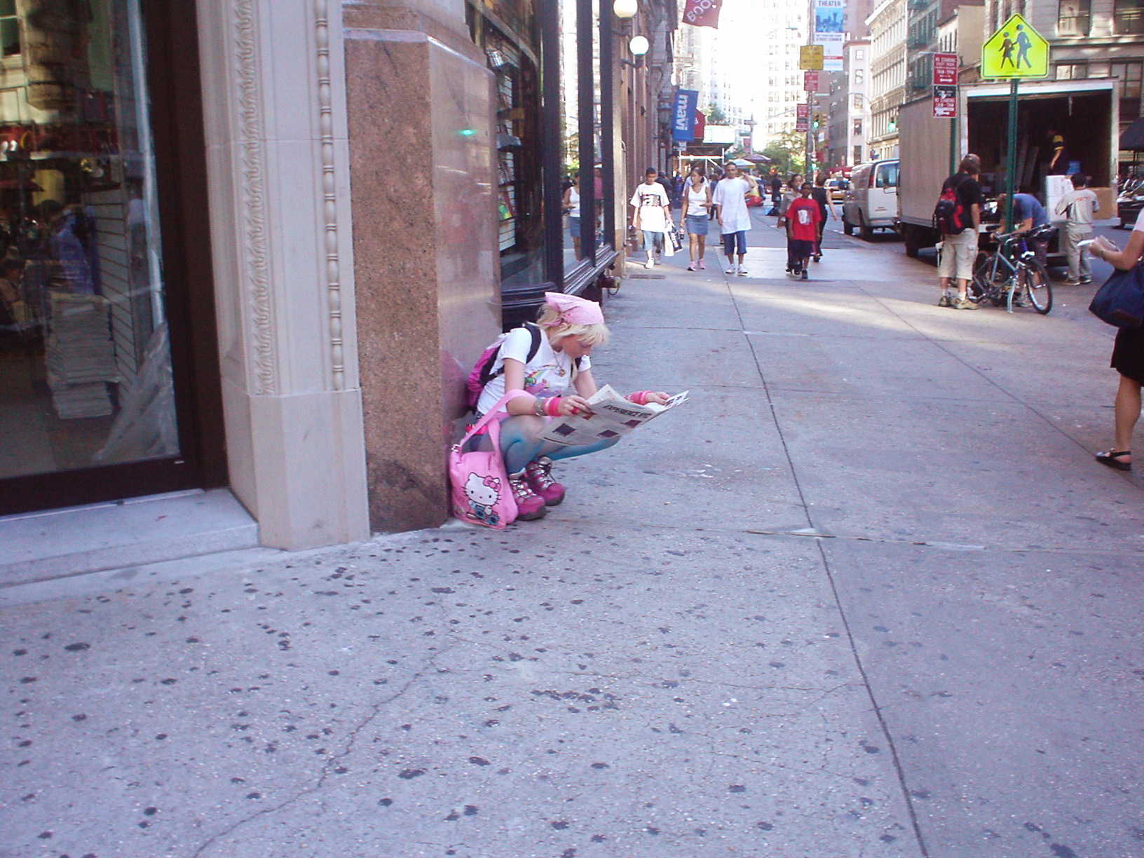 Pink girl reading paper up the street from Strand Books